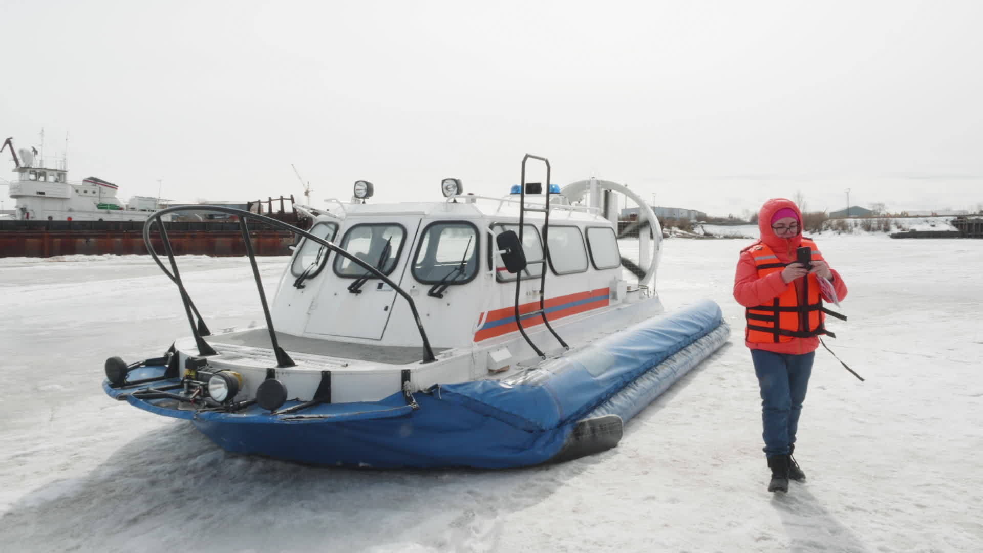 在寒冷的冬季湖上穿着橙色夹克的女性在冰雪湖上乘坐摩天轮视频的预览图