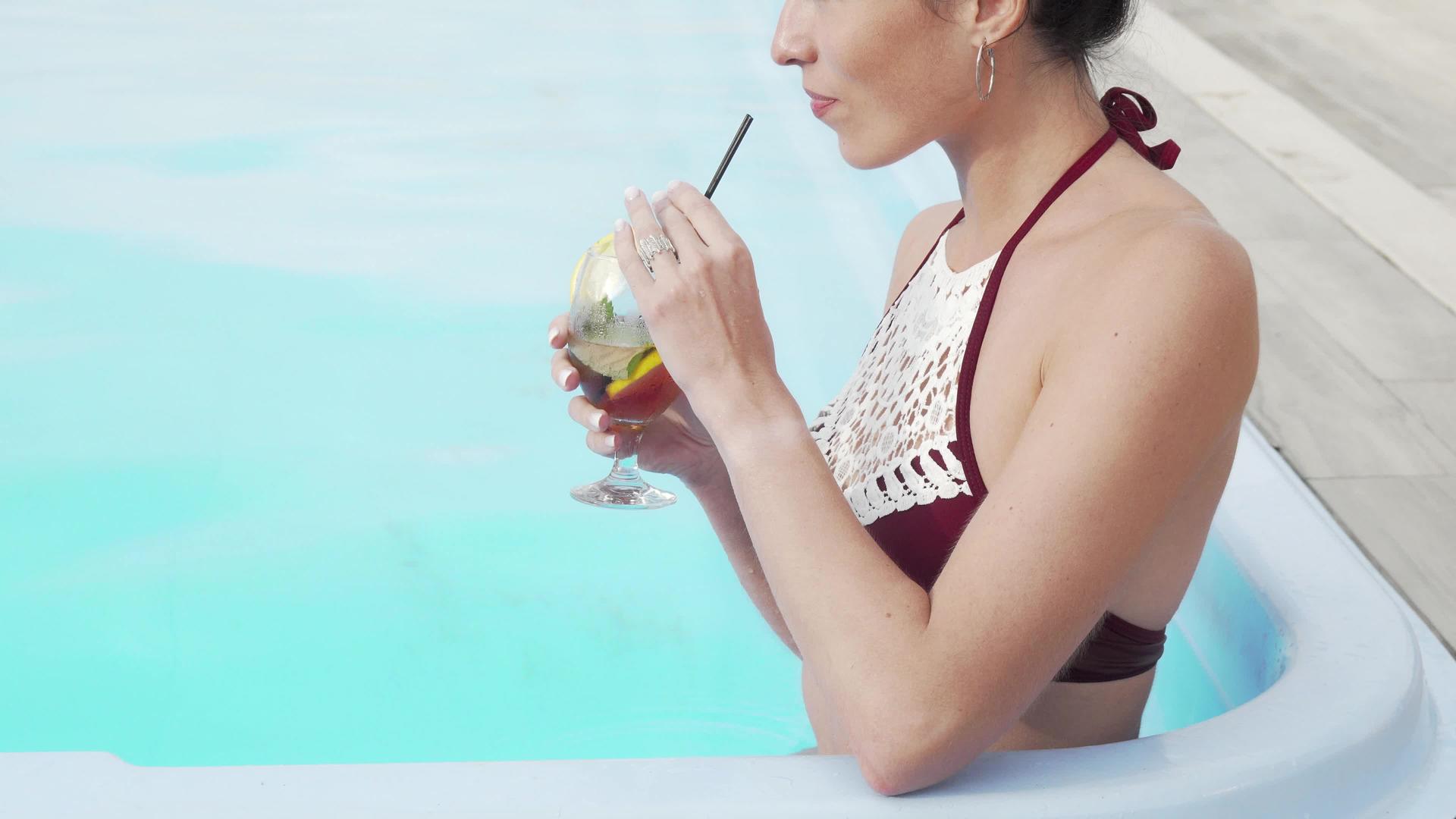 一个在游泳池里笑着喝鸡尾酒的快乐女人被拍到了视频的预览图