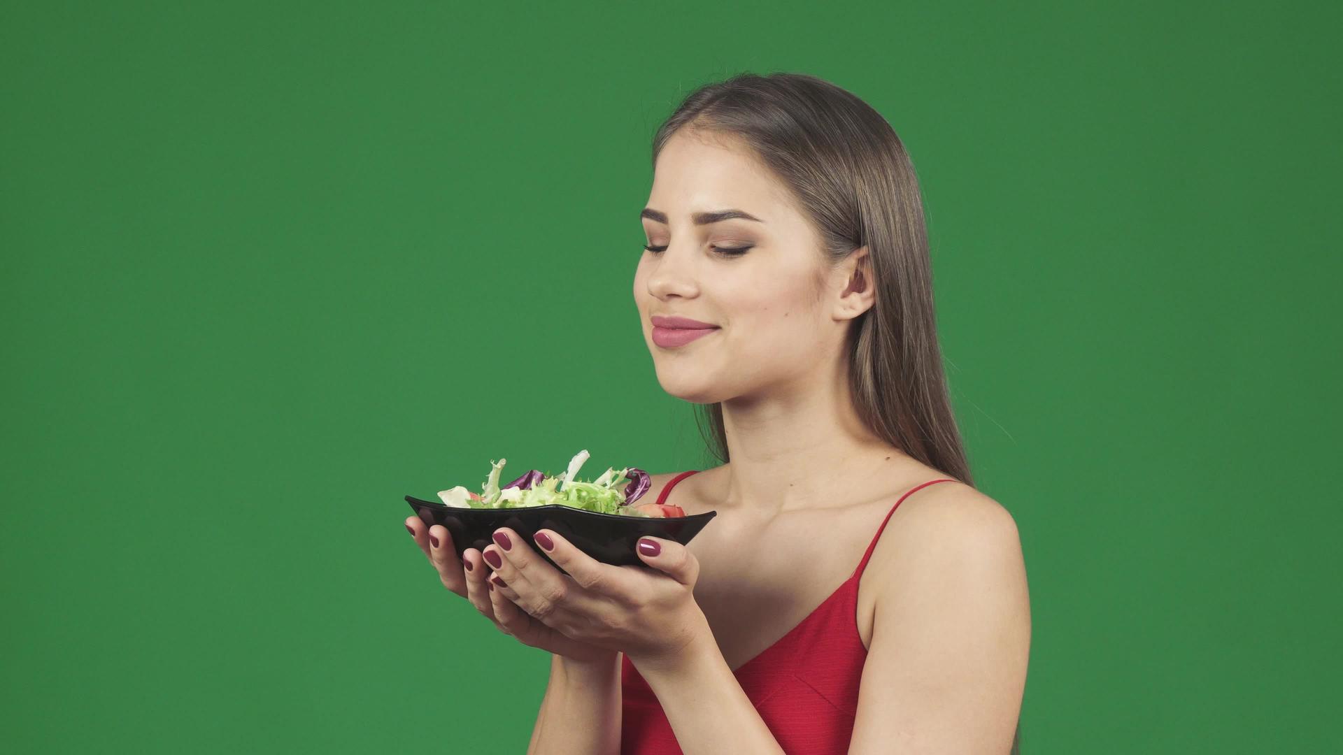 美丽美丽的健康女人闻着美味沙拉的香味开心地笑着视频的预览图