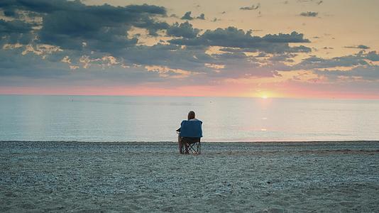 坐在折叠的旅游椅上女人们在海边享受日落视频的预览图