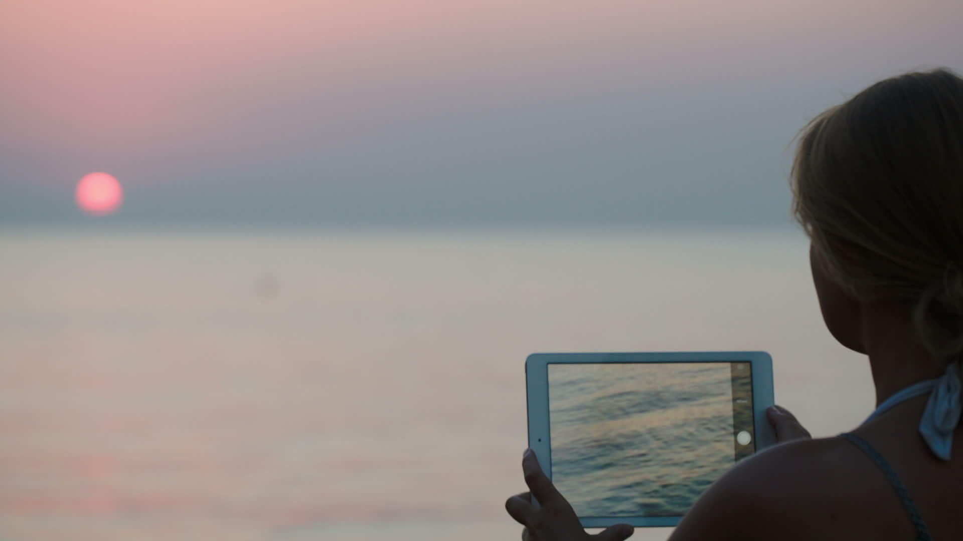 女性使用平板电脑制作日落照片视频的预览图