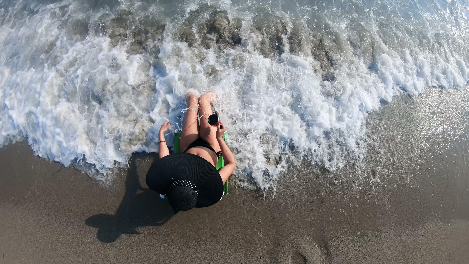 一个戴着草帽的性感迷人的女人坐在海滩上度假视频的预览图