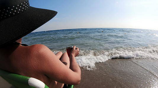 女性草帽和女性草帽坐在海边沙椅上欣赏风景视频的预览图