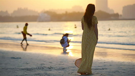白色沙滩上日落时可爱快乐的小女孩视频的预览图
