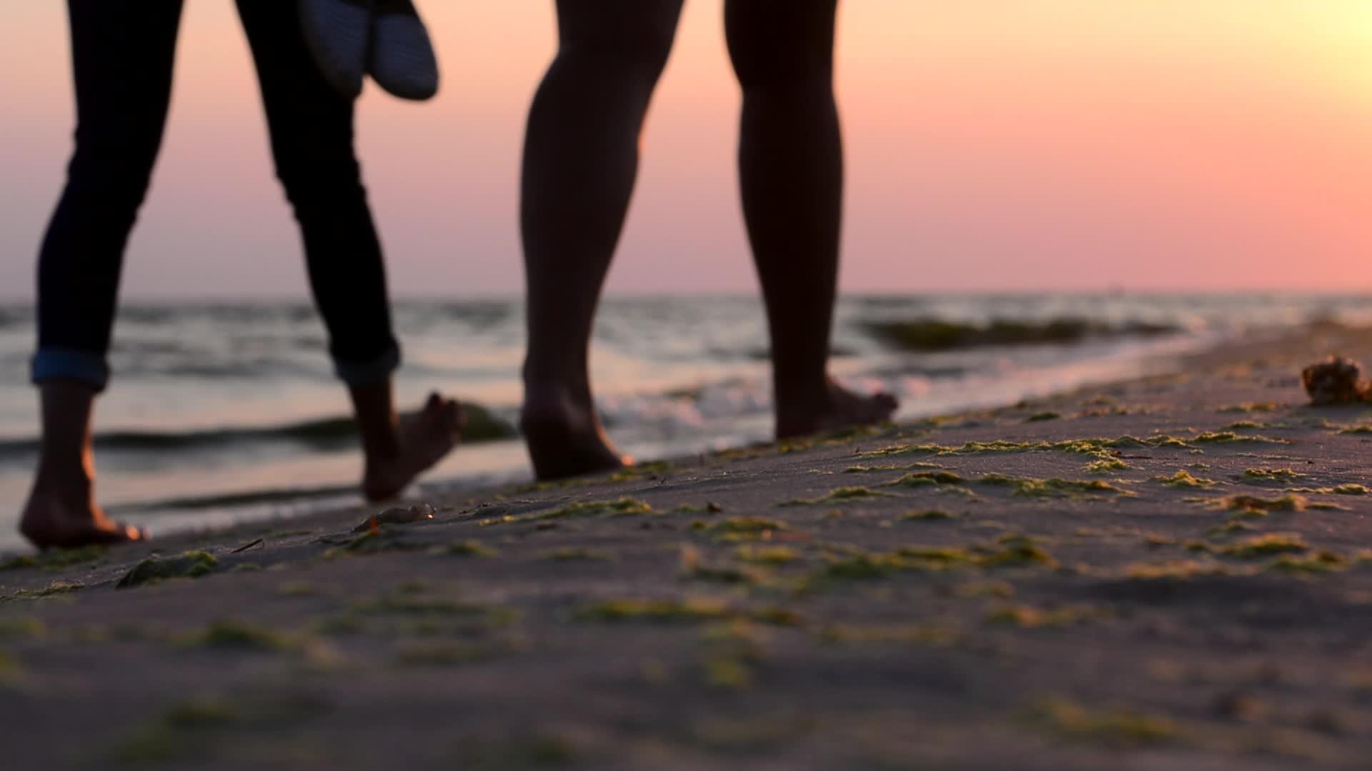 日落时在海滩上赤脚走路的女孩视频的预览图