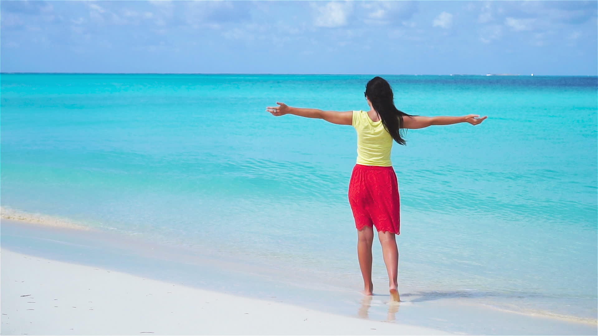 一个在浅水中快乐的女孩在海滩上慢慢地走着视频的预览图