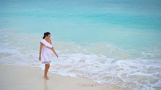 在浅水中行走一个女人在白色沙滩上的顶部视频的预览图