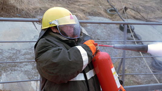 女消防员戴着防护头盔和制服在烧烤架上用灭火器灭火视频的预览图