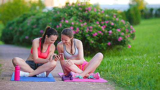 年轻活跃的健身女性在户外锻炼和看智能手机视频的预览图
