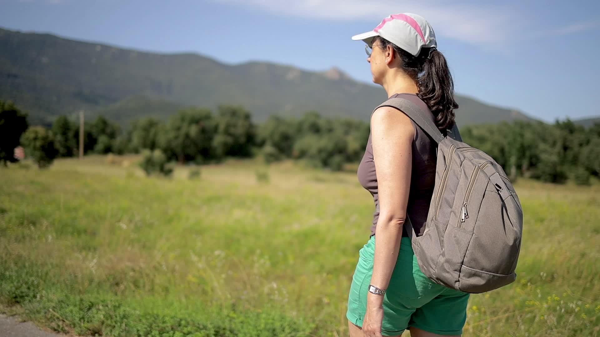 年轻的西班牙女青年在美丽的山景中慢慢地走在路上视频的预览图