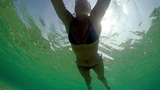 一个年轻的女人在宁静的海水上游泳夏天阳光明媚视频的预览图