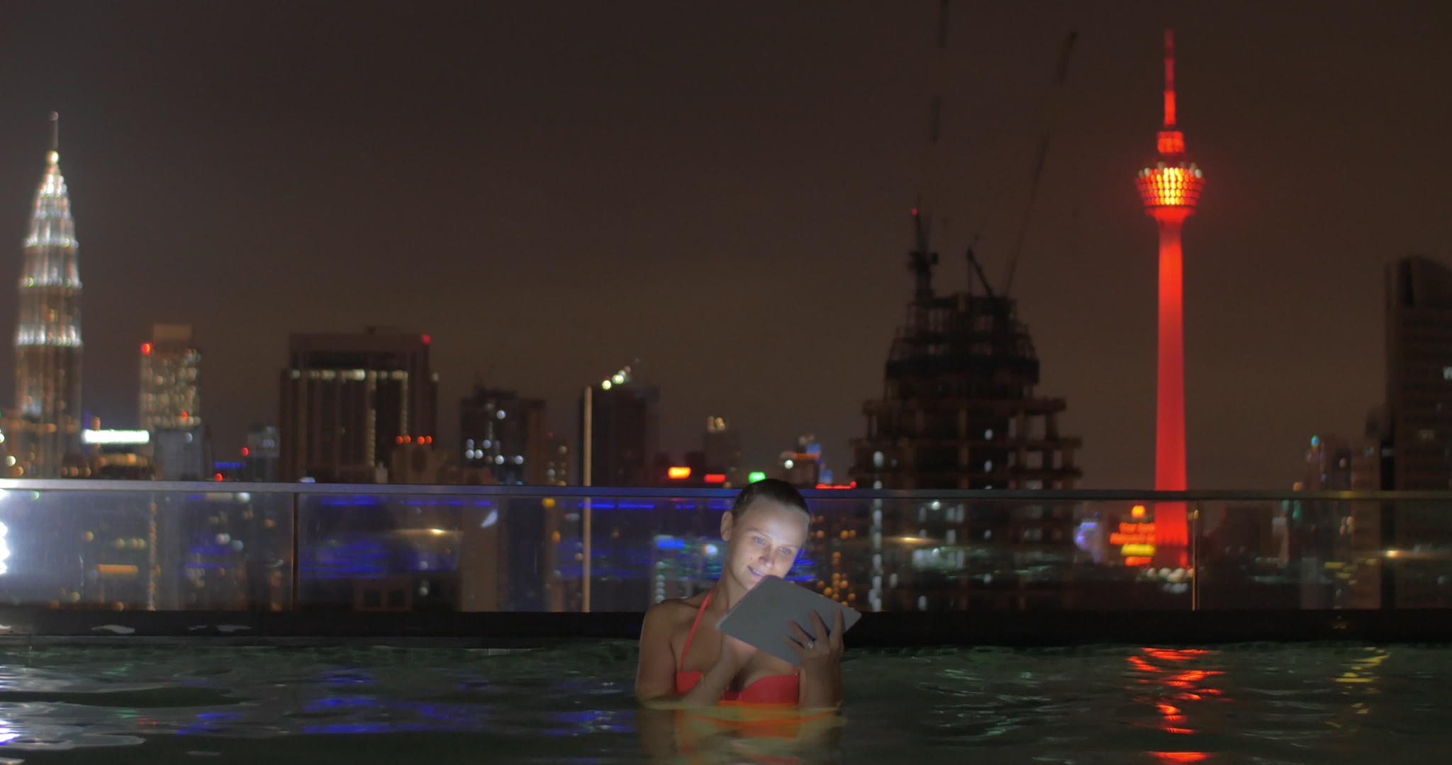 在摩天大楼屋顶的游泳池中使用平面和夜景比较视频的预览图