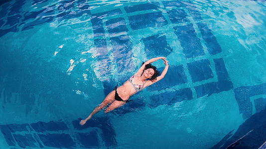 漂浮在游泳池水面上的年轻女性视线最高视频的预览图