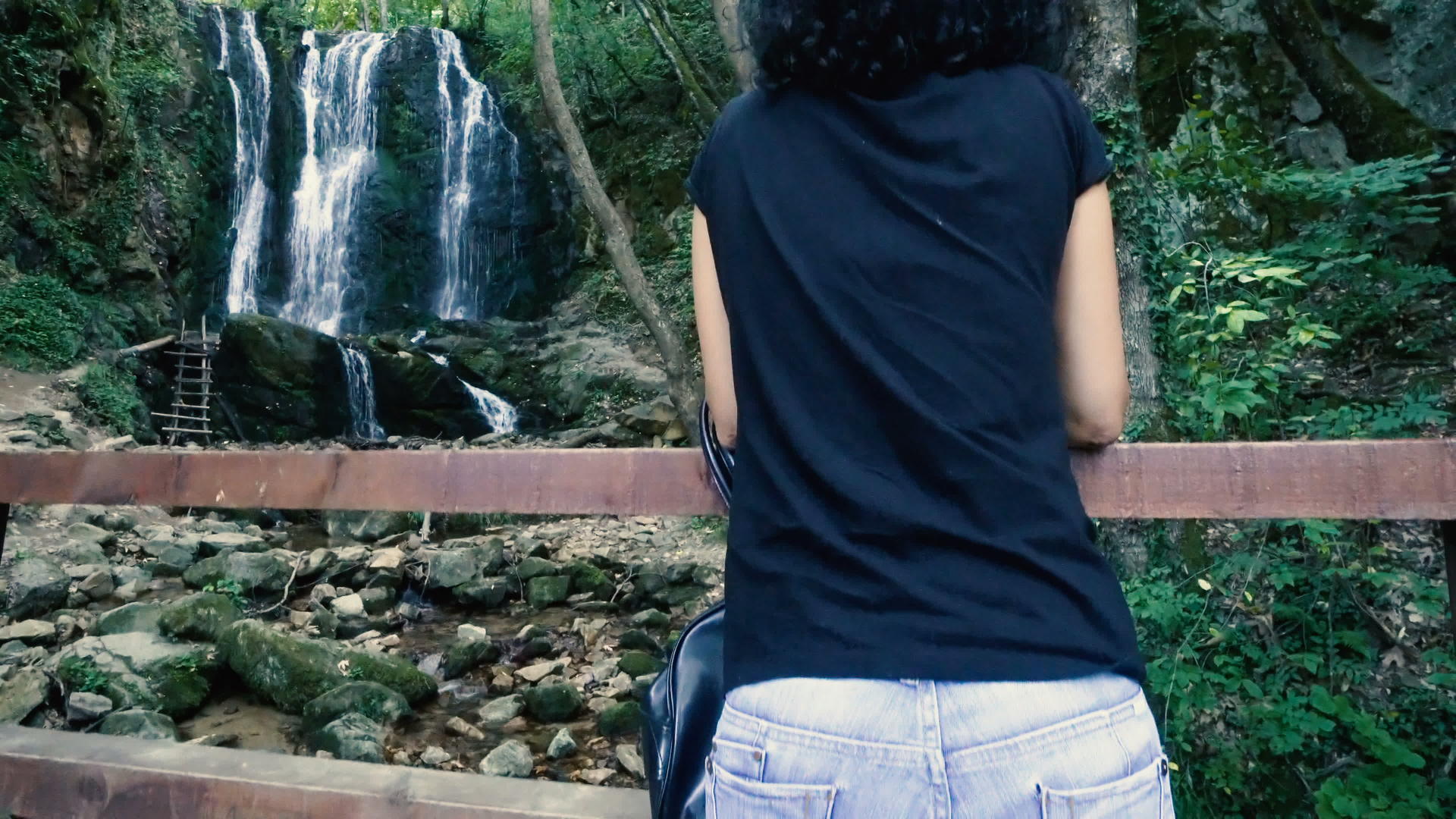 卷发的女人享受瀑布的风景视频的预览图