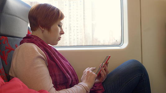 女人在火车上用她的智能手机阅读视频的预览图