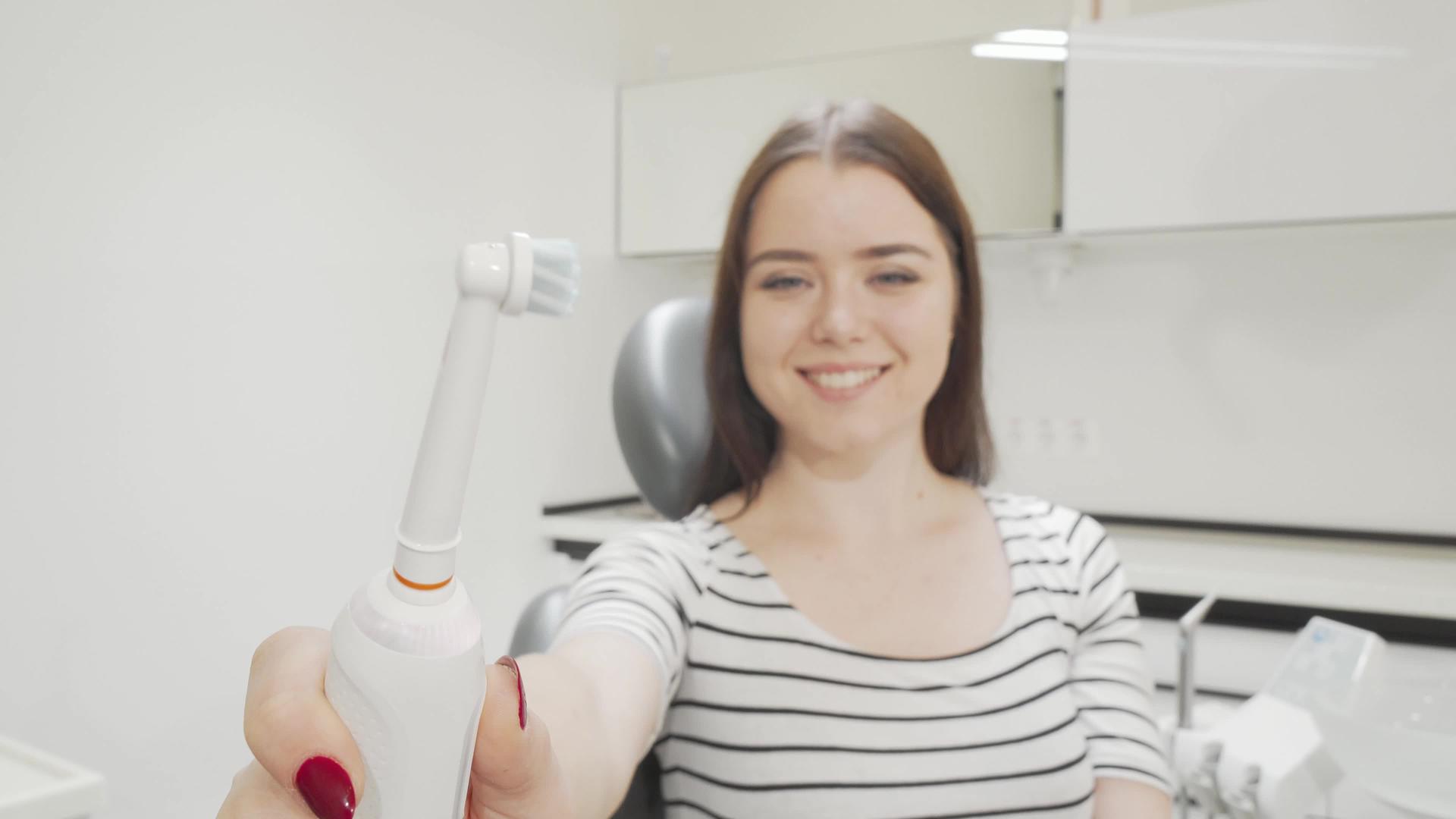 选择性地关注一个快乐女人手中的电动牙刷视频的预览图
