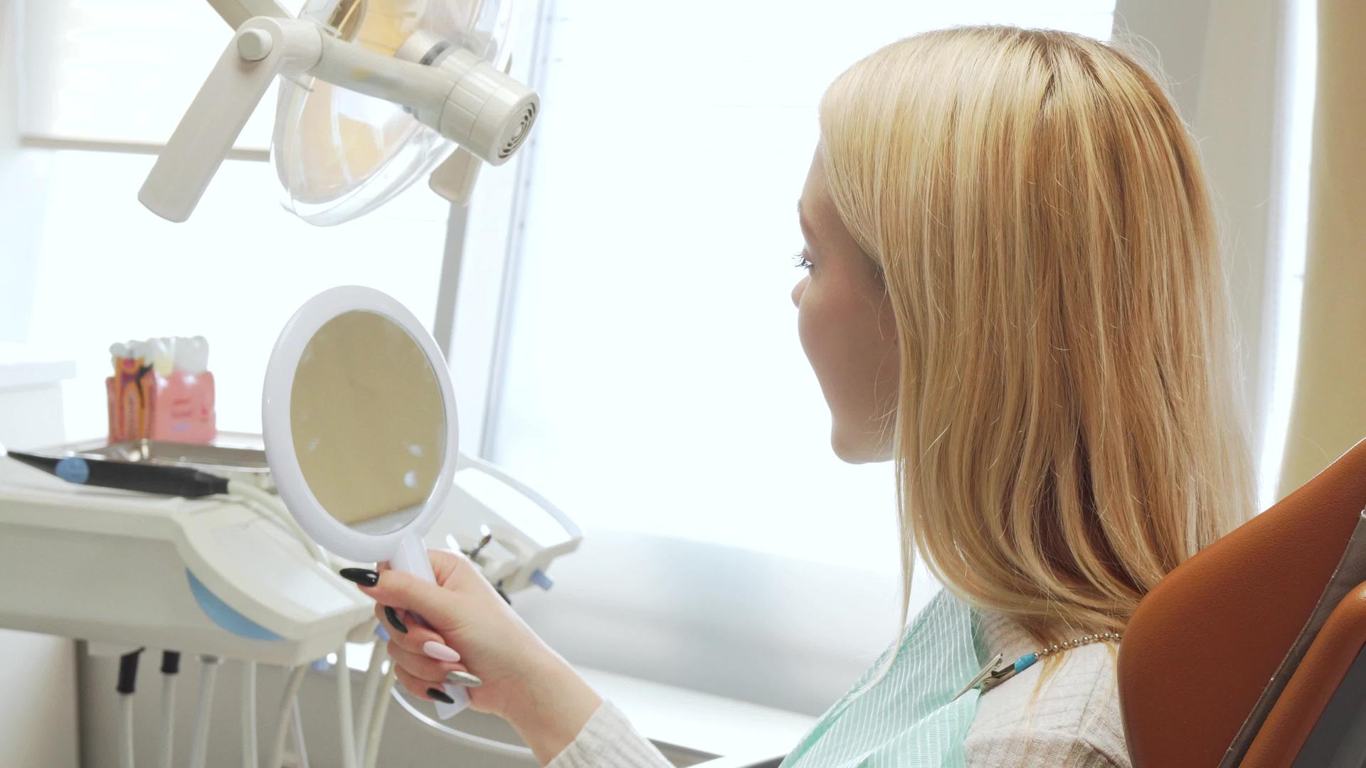 一名女性患者在牙科诊所的后视镜中照镜子视频的预览图