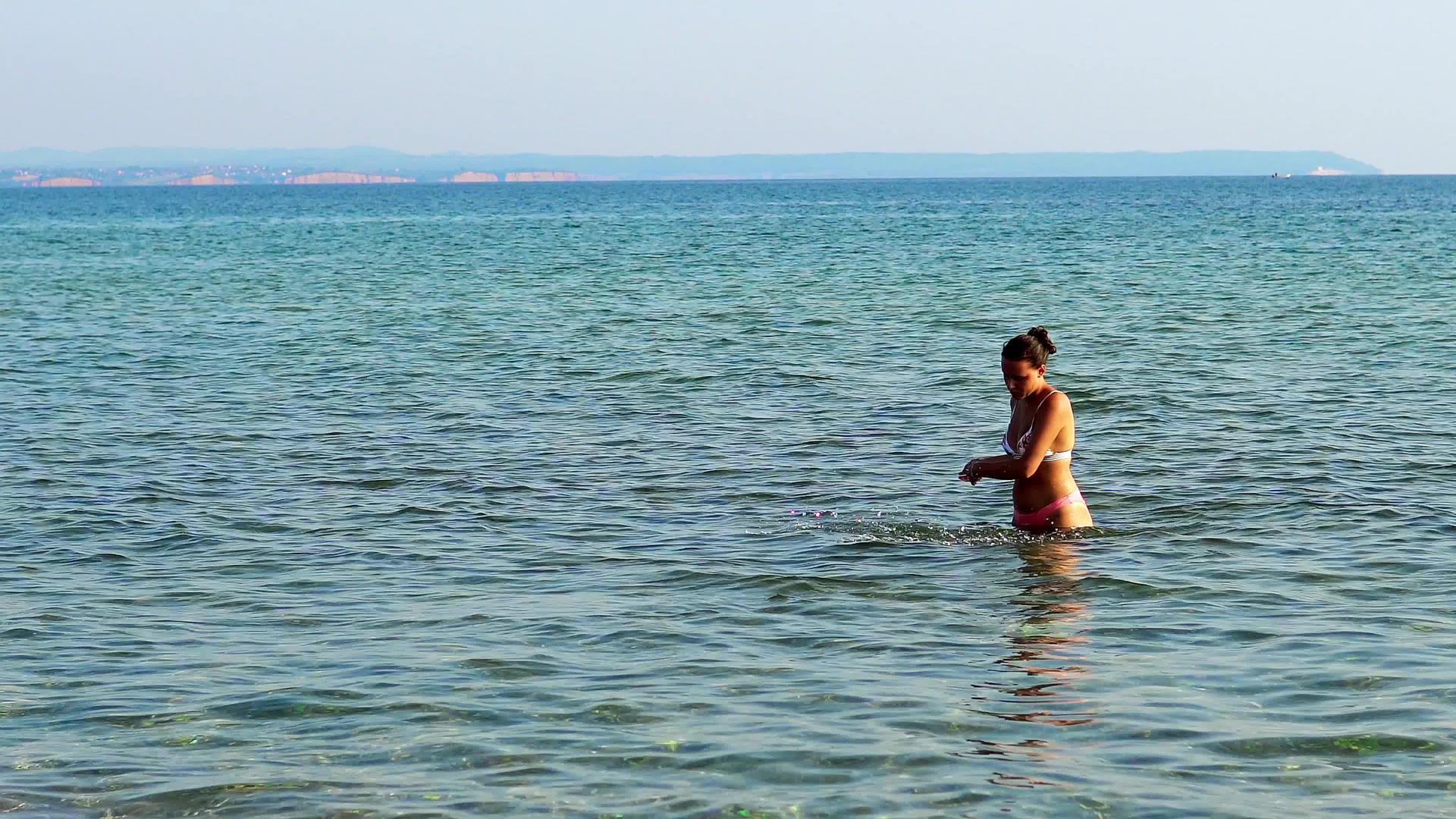 孤独的年轻女子独自在浅水中玩耍用手喷洒视频的预览图