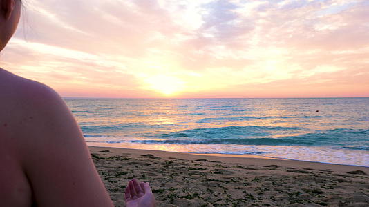 女人坐在沙滩上做日出瑜伽视频的预览图