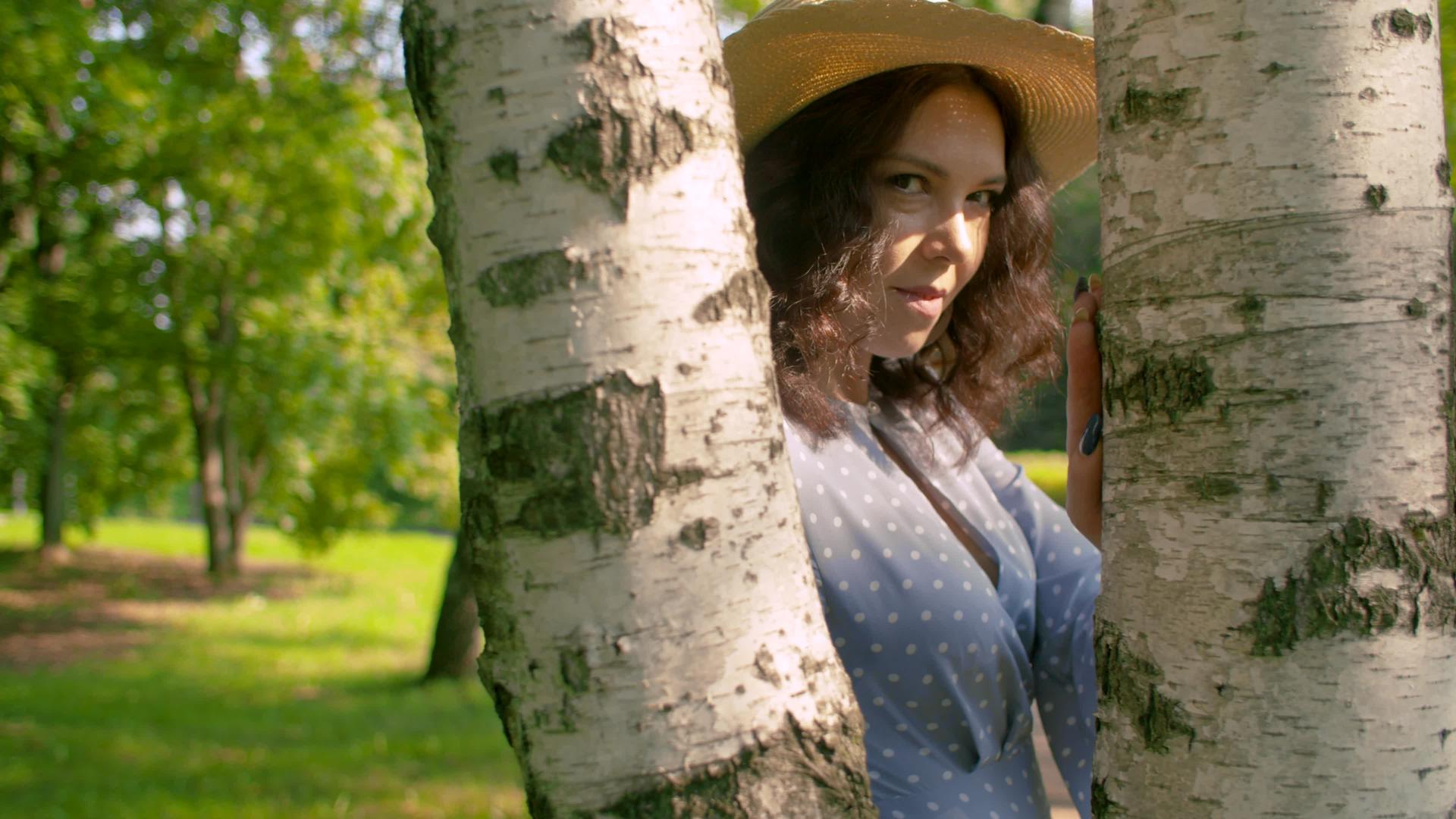 迷人的年轻女子站在树枝旁边视频的预览图