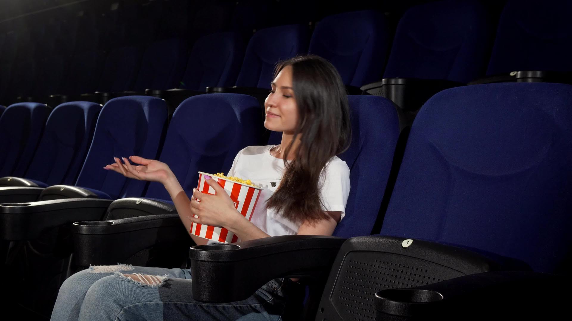 在电影院的年轻女性在电影院享受电影视频的预览图