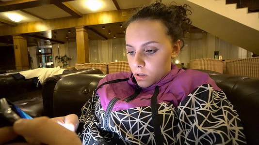坐在沙发上的年轻女性有智能手机视频的预览图