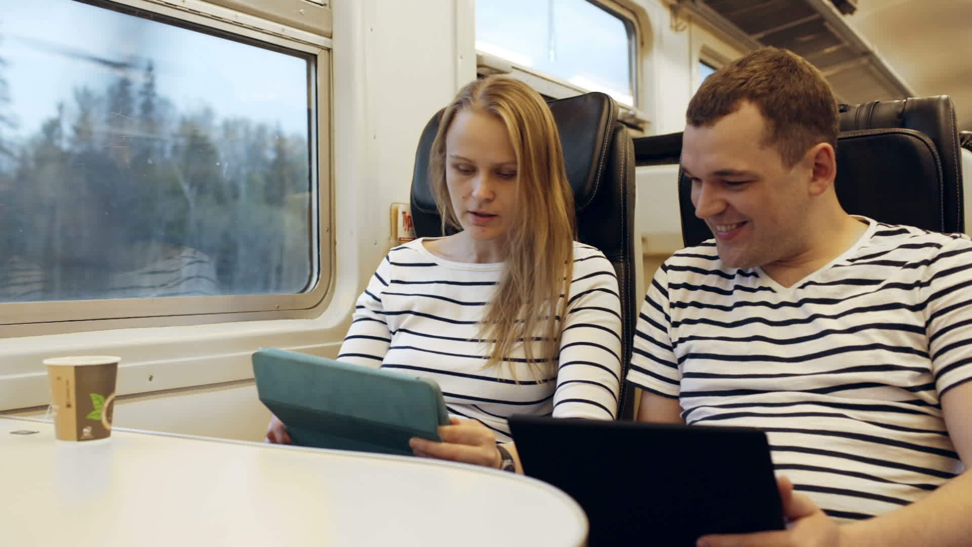 在火车上交谈的年轻人看着平板电脑视频的预览图