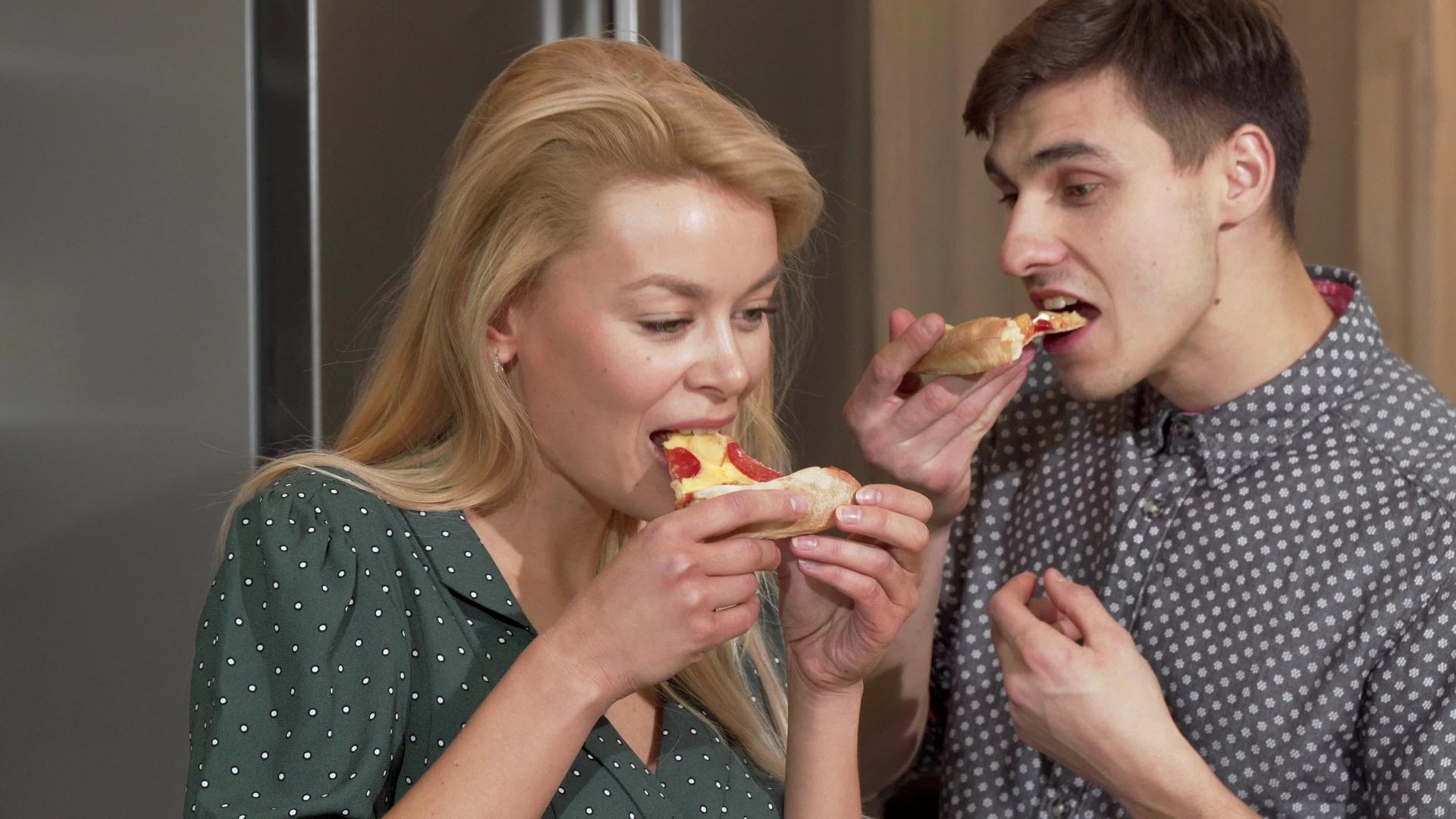快乐的夫妇在厨房的新公寓里享受美味的披萨视频的预览图