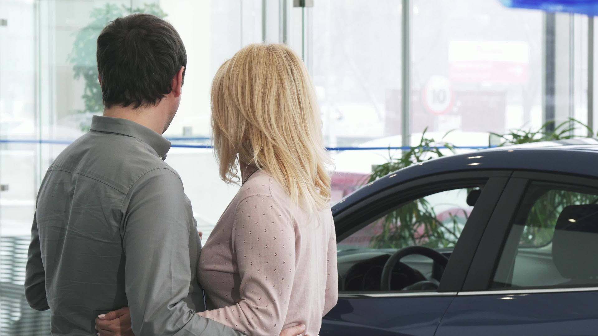 一对成熟的夫妇在经销商检查一辆新车的后视镜头视频的预览图