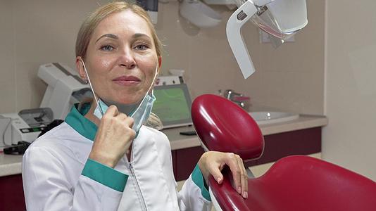 成熟的女牙医脱下医疗面具微笑着微笑视频的预览图