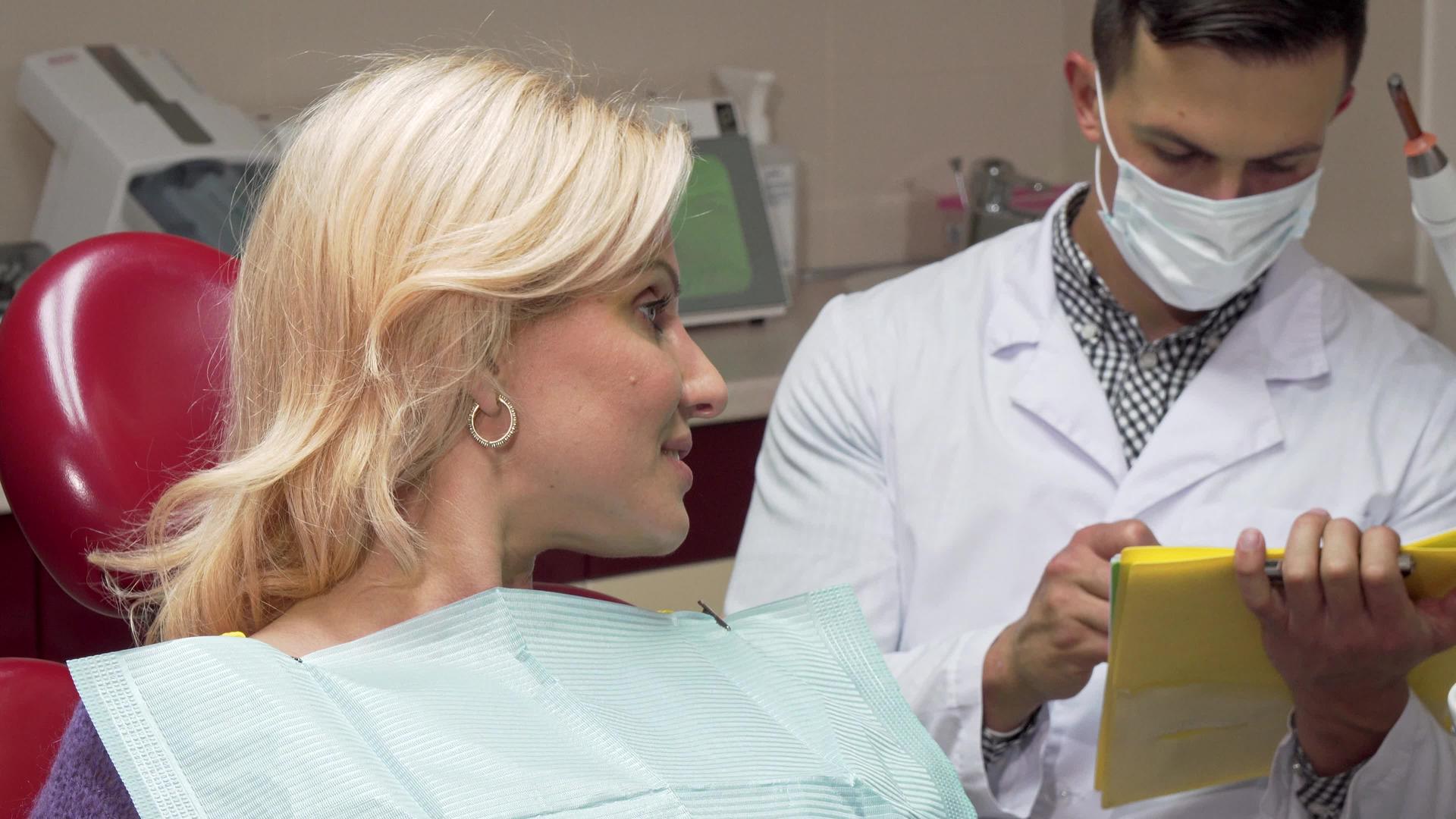 快乐的女性病人坐在牙医面前的牙科椅子上露出拇指视频的预览图