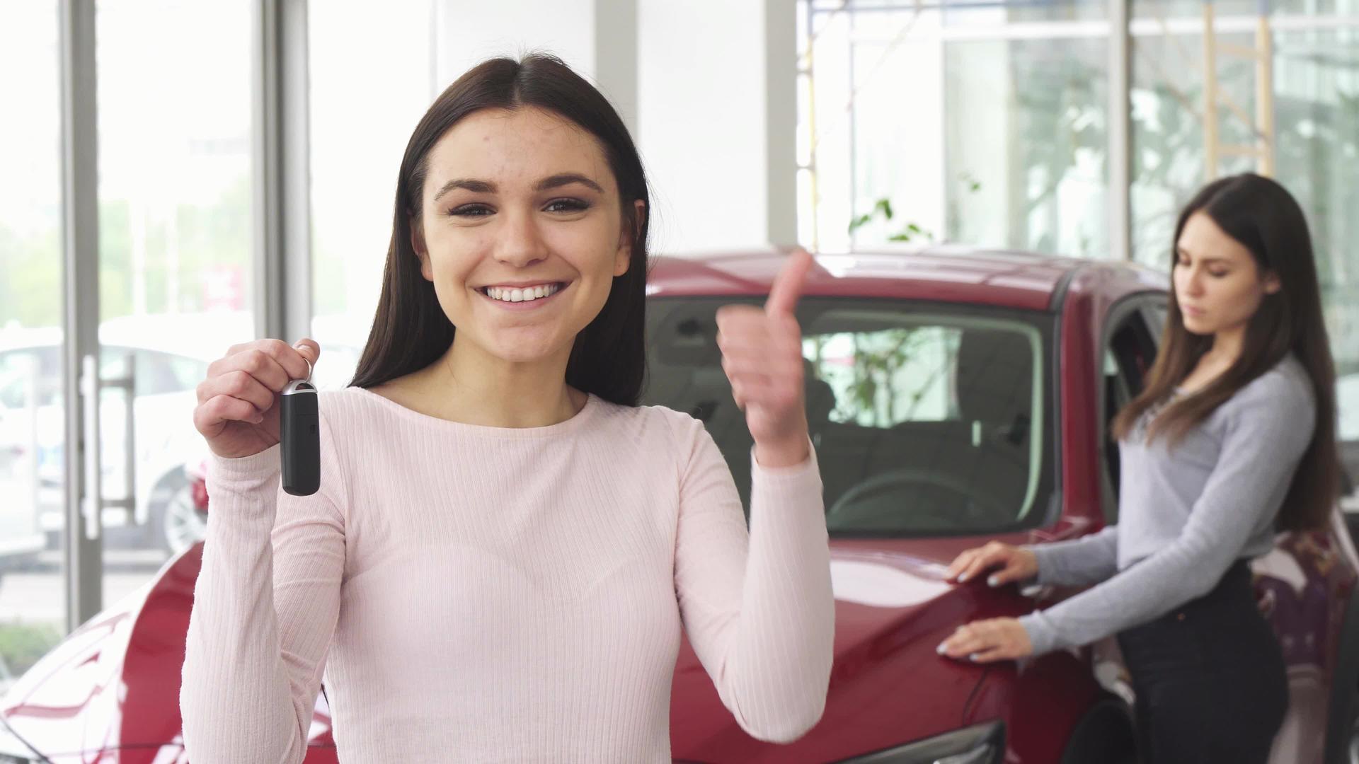 快乐的年轻女子用车钥匙的拇指举起手视频的预览图
