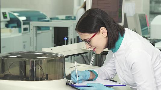 年轻女性化学家在现代实验室做笔记视频的预览图