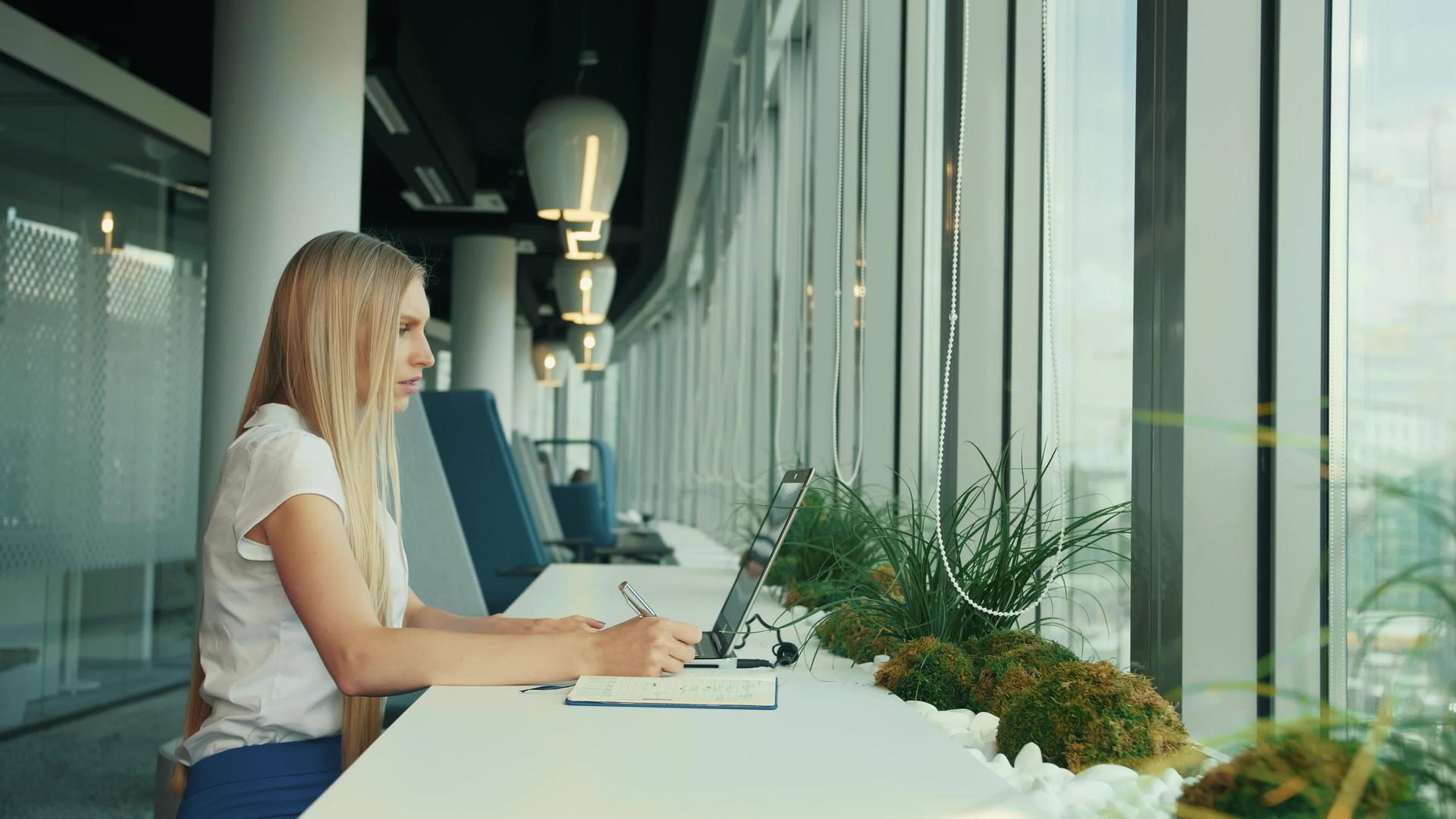 在新办公室使用笔记本电脑的女商人坐在现代办公室的窗户里视频的预览图
