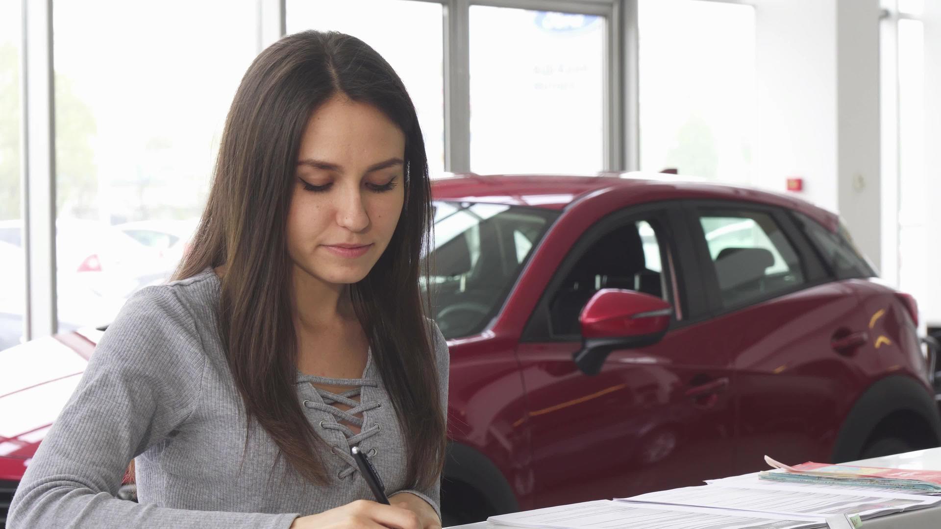 有吸引力的年轻女司机在汽车经销商填写文件视频的预览图