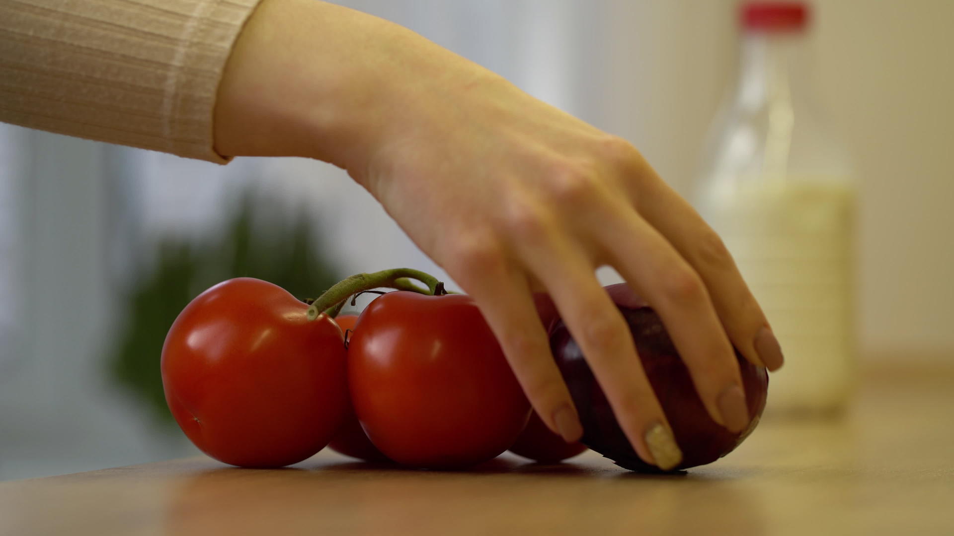 年轻女子把新鲜蔬菜、西红柿和洋葱放在厨房的桌子上视频的预览图