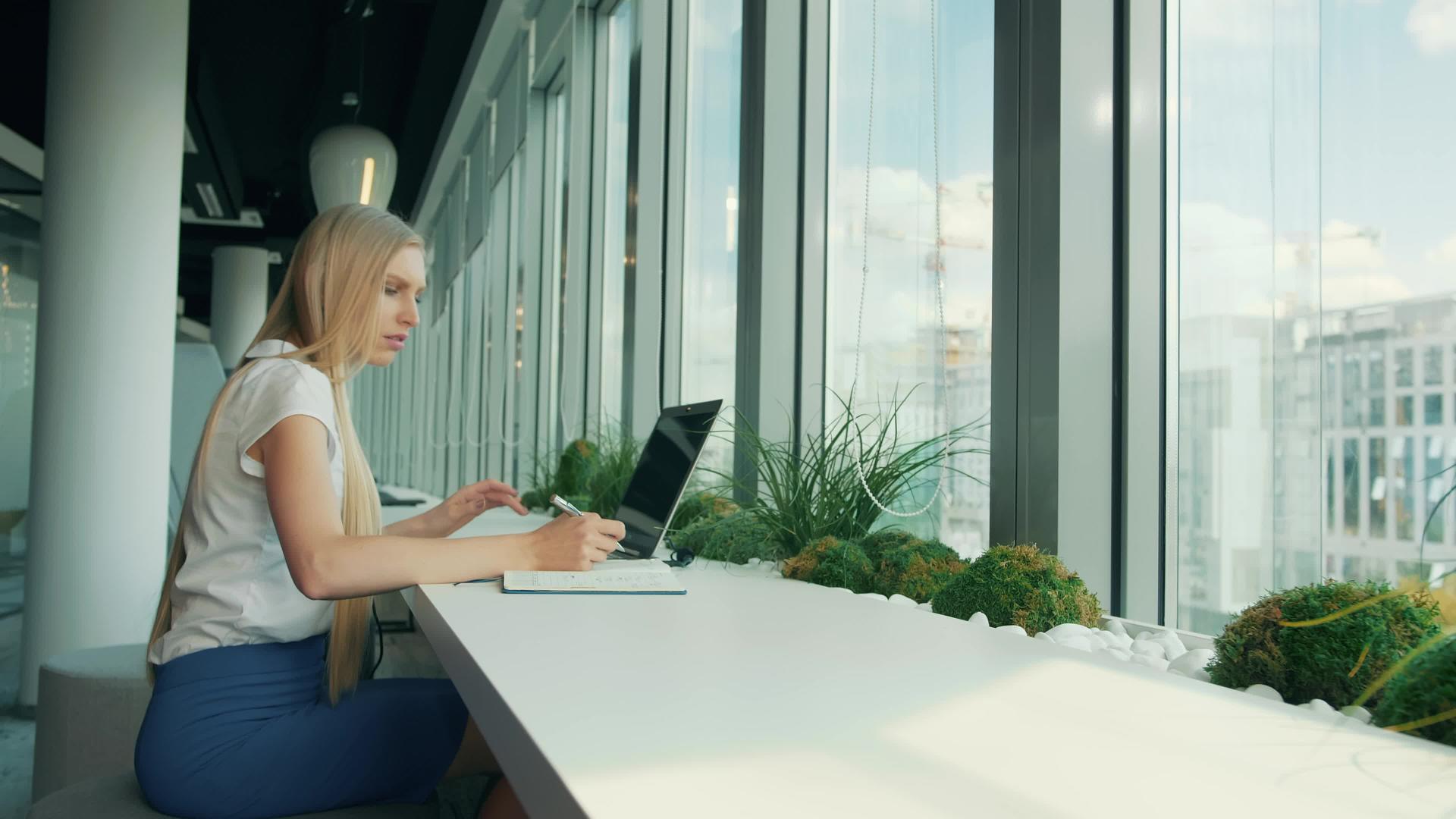 在现代办公室的窗户附近盖电脑和文件的正式女性视频的预览图