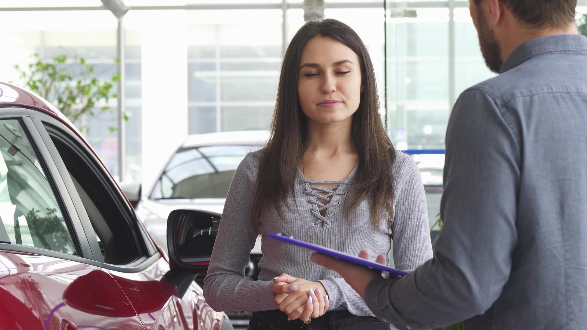 这位年轻女子与汽车经销商的推销员交谈视频的预览图