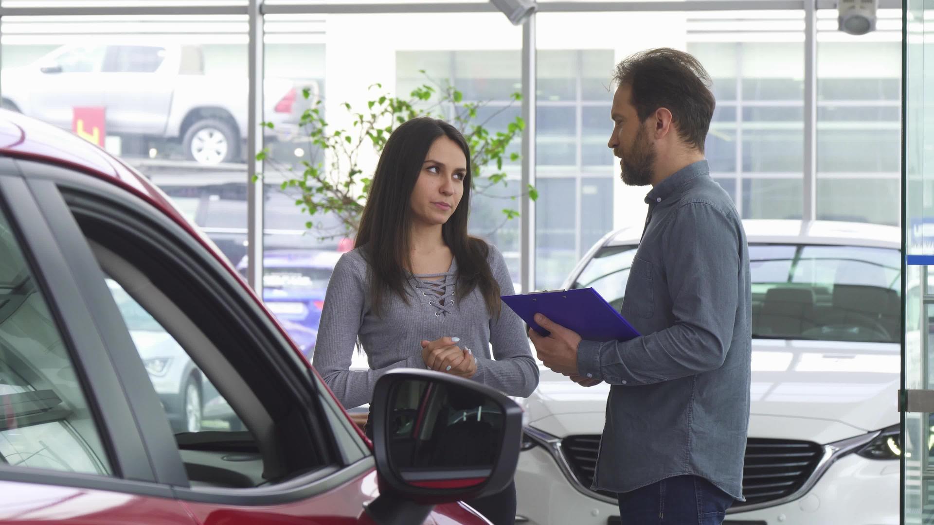 成熟的销售人员与女顾客交谈为她提供一辆汽车视频的预览图