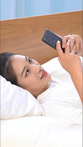 女生躺在床上打字聊天竖构图视频视频的预览图