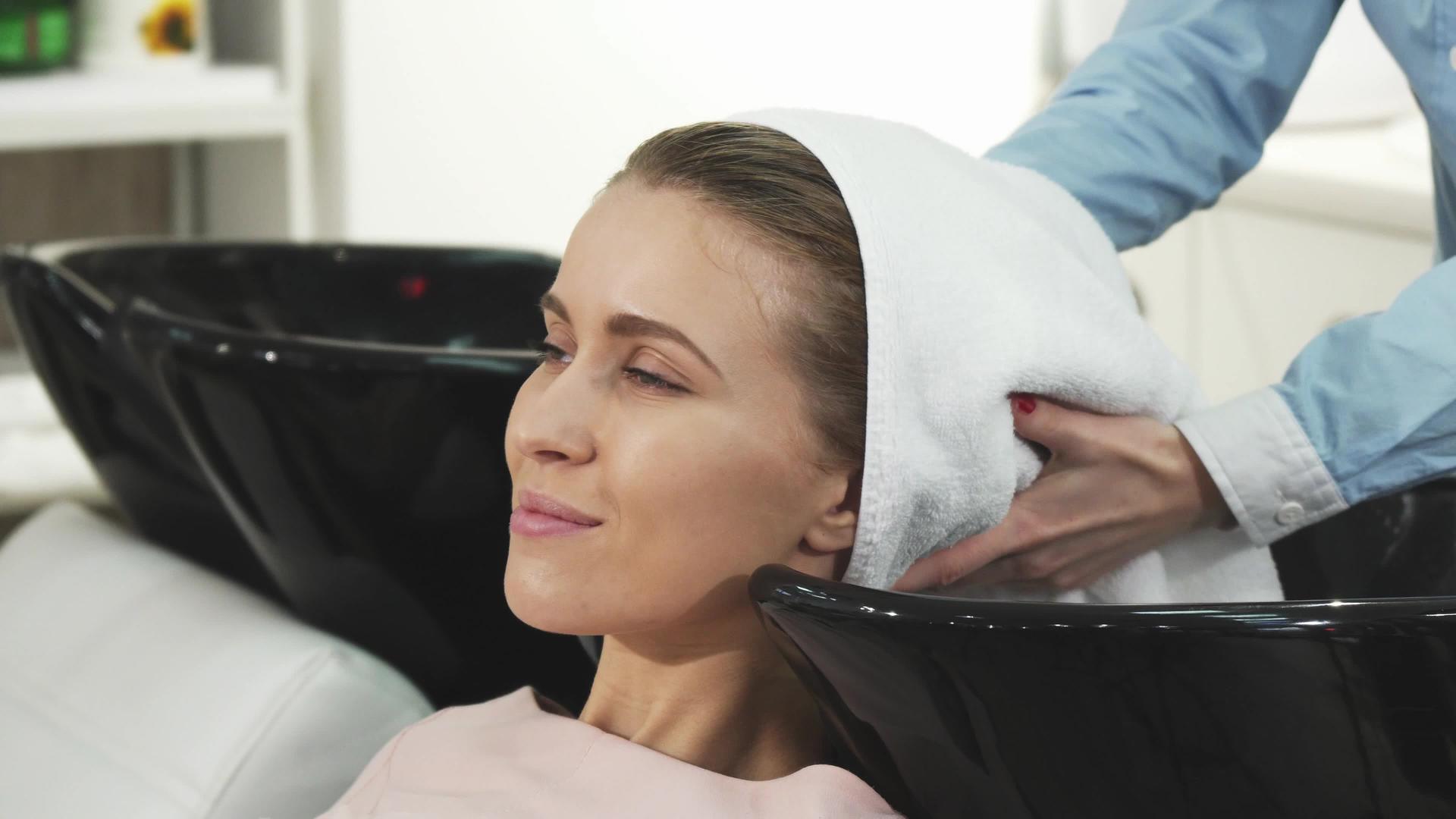 一个漂亮的女人微笑着让一个专业的理发师擦干她的头发视频的预览图