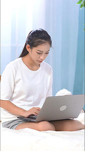 女生坐在床上使用电脑竖构图视频视频的预览图