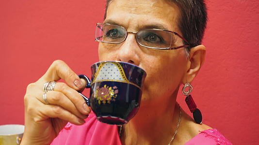 老年妇女的肖像在红色背景下喝茶视频的预览图