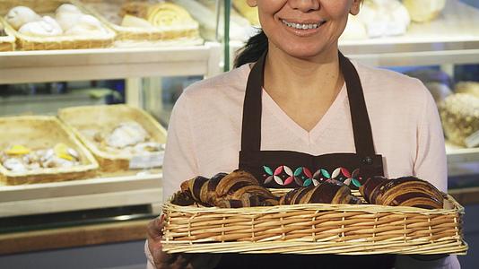 一个快乐的女面包师装满了一篮羊角面包蛋糕视频的预览图