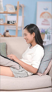 居家女生在沙发上开心的看电脑竖构图视频视频的预览图