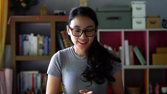 快乐的女人戴着眼镜笑着打视频电话视频的预览图