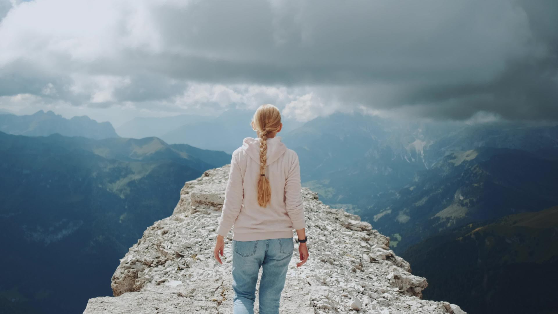 看到一个金发女人在云下的山顶上行走视频的预览图