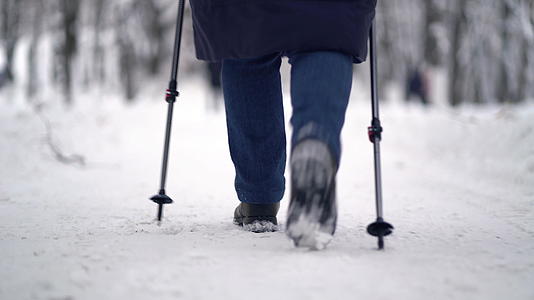 活跃的老年妇女用登山杖训练北欧步行冬天在户外练习视频的预览图