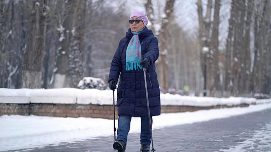 活跃的老年妇女用登山杖训练北欧步行 冬天在户外练习视频的预览图