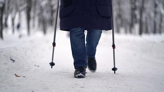 活跃的老年妇女用登山杖训练北欧步行冬天在户外练习视频的预览图